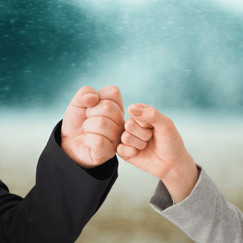 Zwei Menschen berühren sich mit geballten Fäusten zum Fistbump als Zeichen von Teamgeist und Zusammenhalt.